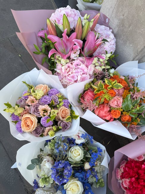 A collection of five vibrant floral bouquets arranged in white and pastel-colored wrapping paper, featuring a variety of fresh flowers including pink lilies, pink hydrangeas, orange and pink roses, pu